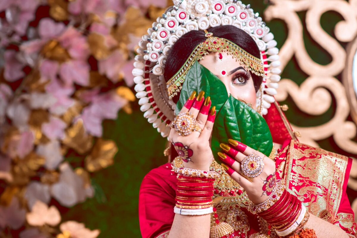 South Asian bride in red saree with vibrant accessories, showcasing cultural elegance.