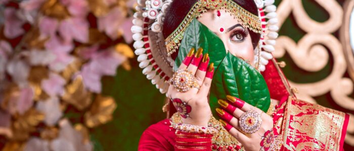 South Asian bride in red saree with vibrant accessories, showcasing cultural elegance.