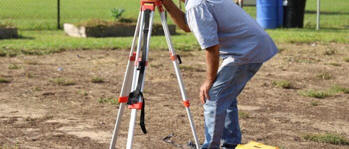 A land surveyor at work using equipment on a field in Tavares, Florida.