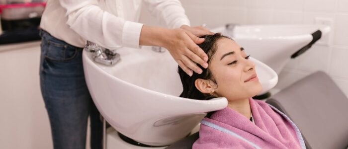 A woman enjoys a relaxing hair wash at a modern salon, symbolizing self-care and pampering.