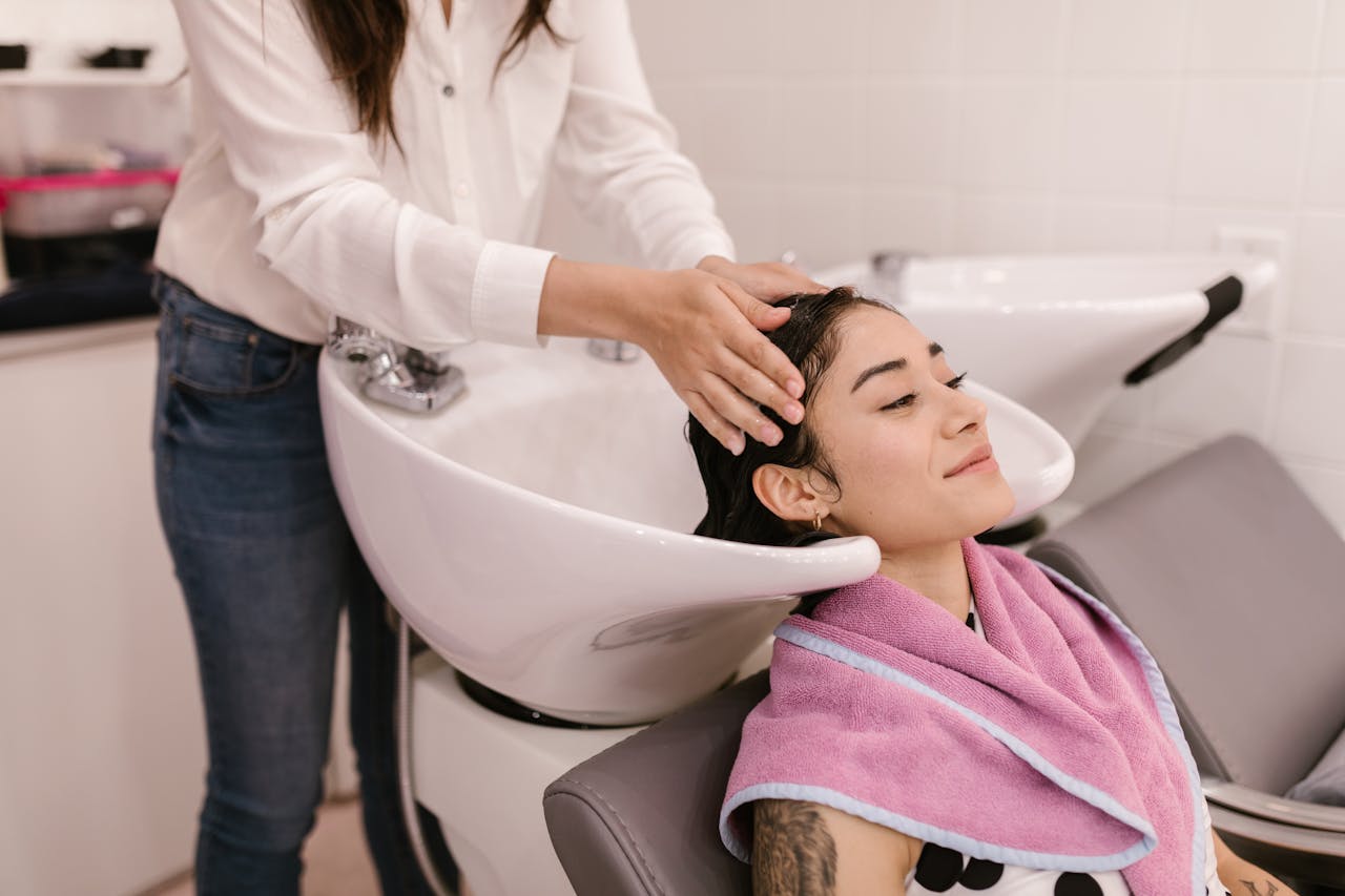 A woman enjoys a relaxing hair wash at a modern salon, symbolizing self-care and pampering.